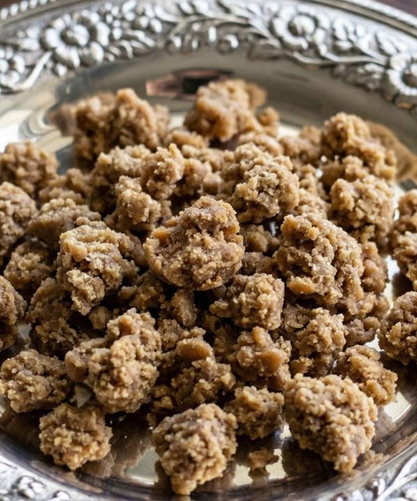 High-potency GMO Cookies THCA crumble concentrate with a golden-brown waxy texture displayed on an ornate silver saucer.